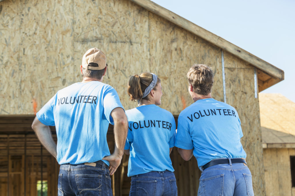 A group of three volunteers helping to build a house for a family in need