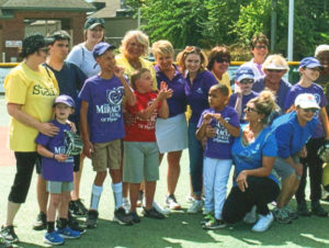 employees volunteering to help disabled children play baseball. 