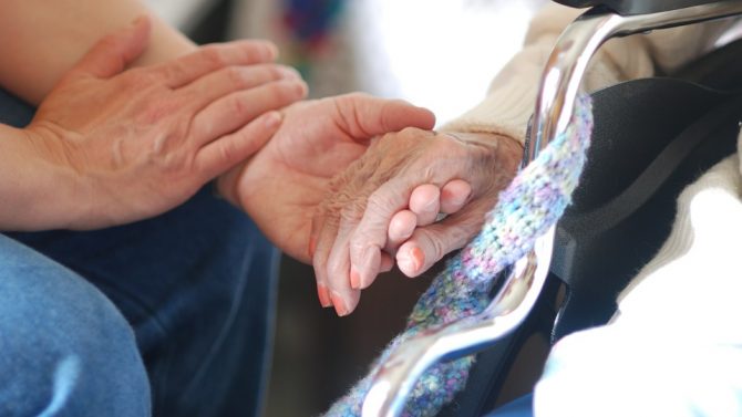 close up of a man holding an elderly woman's hand