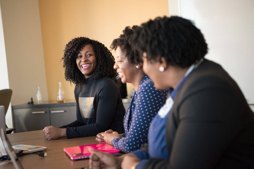 three woman smiling while in a meeting. 
