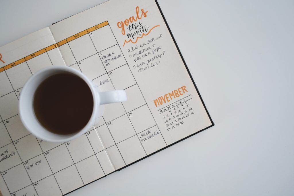 cup of coffee sitting on top of a monthly goal planner