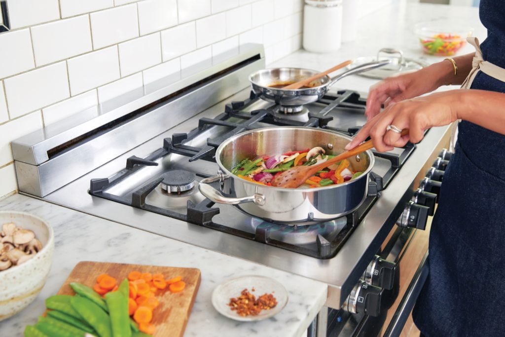 woman sauteing vegetables in a pan