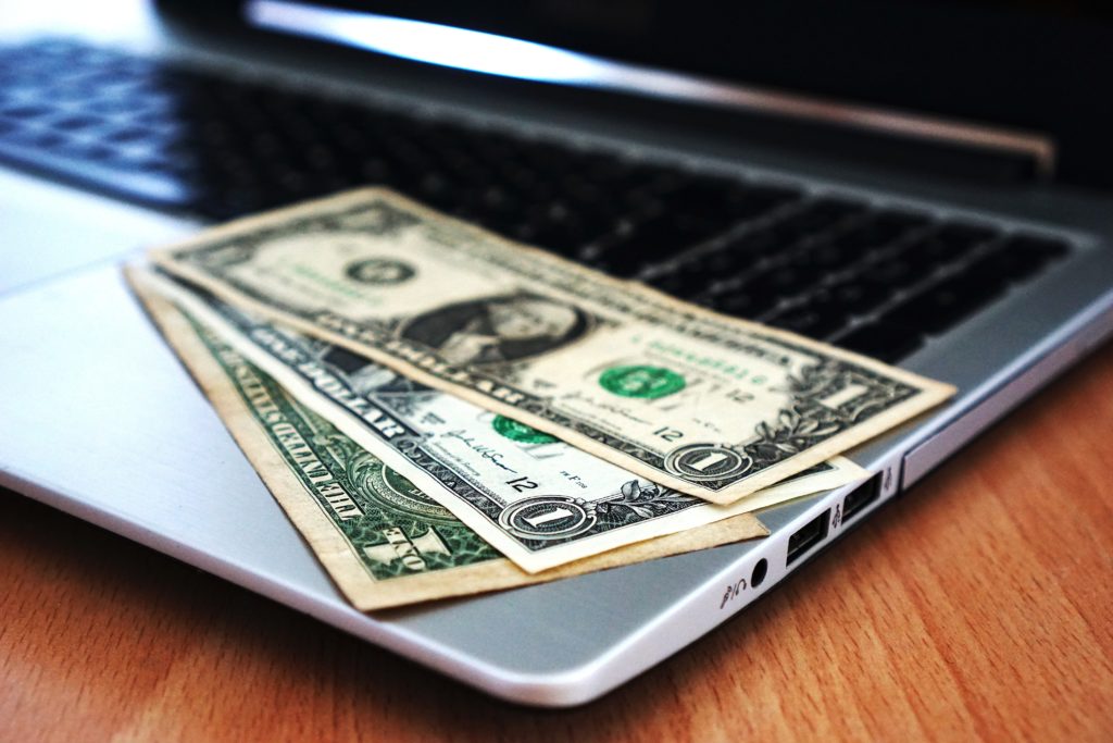 dollar bills sitting on a laptop keyboard