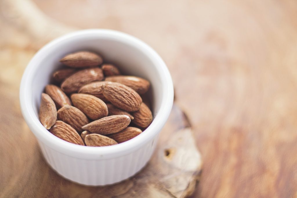 almonds in a white bowl on a wooden table 