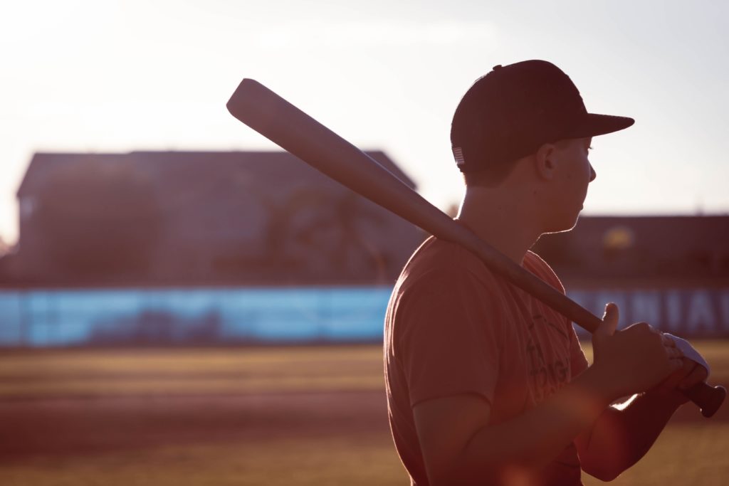 teenage boy holding a baseball bat over his shoulder at a baseball stadium 