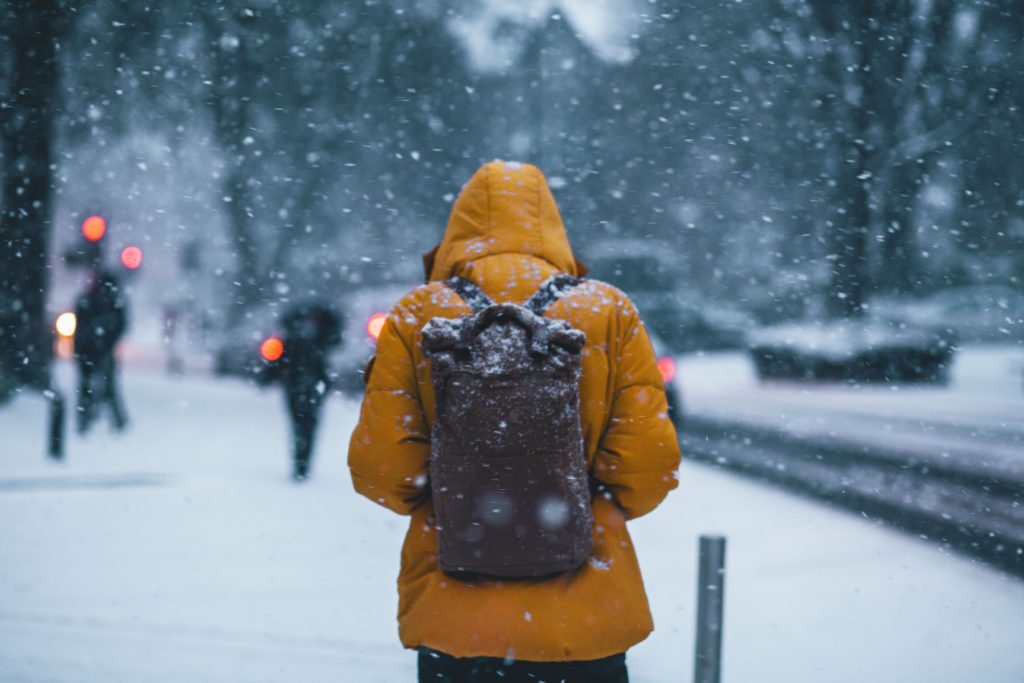 man experiencing the winter blues while walking to work in the snow