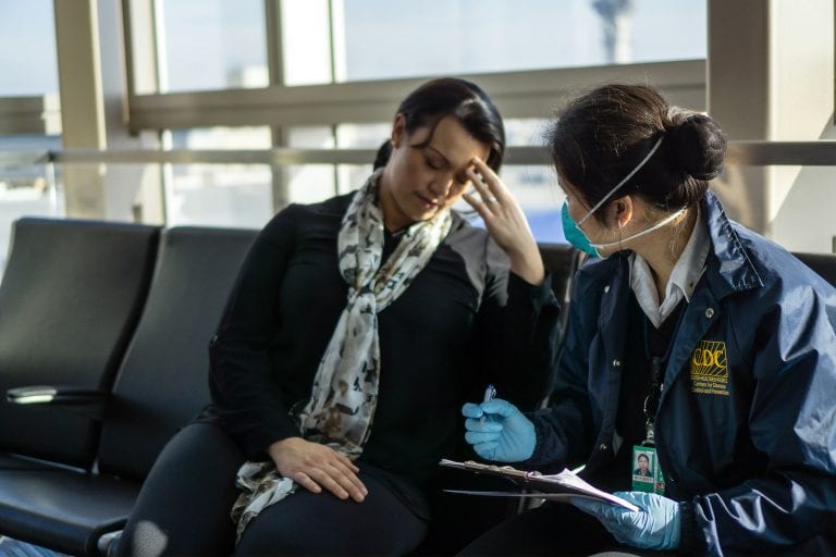 woman in an airport experiencing coronavirus symptoms