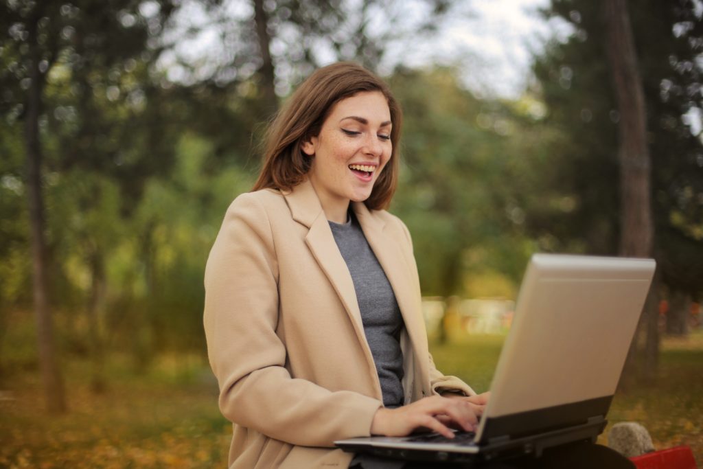 woman sitting in a park working on a computer