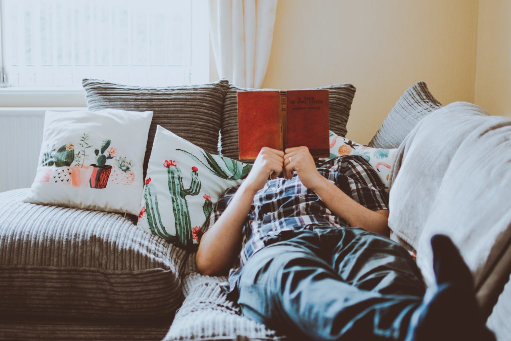 man laying on the couch reading a book