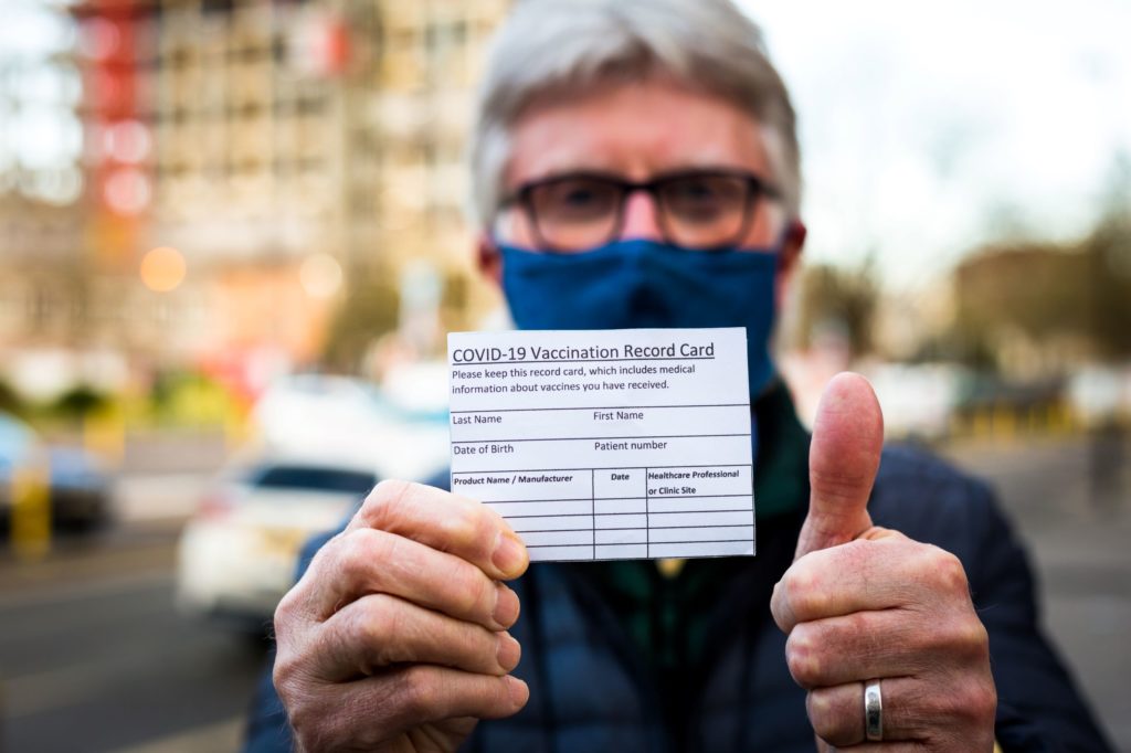older man holding his covid-19 vaccination card