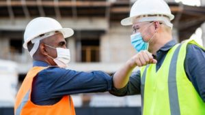 two construction workers touching elbows instead of shaking hands at work