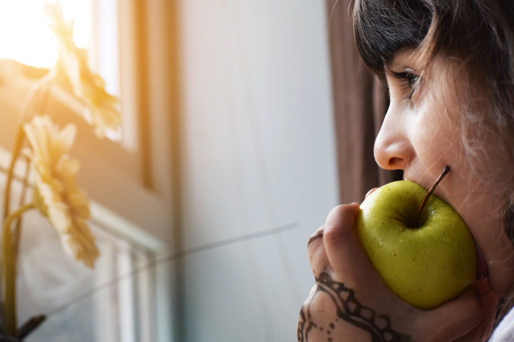 woman eating apple while looking out the window